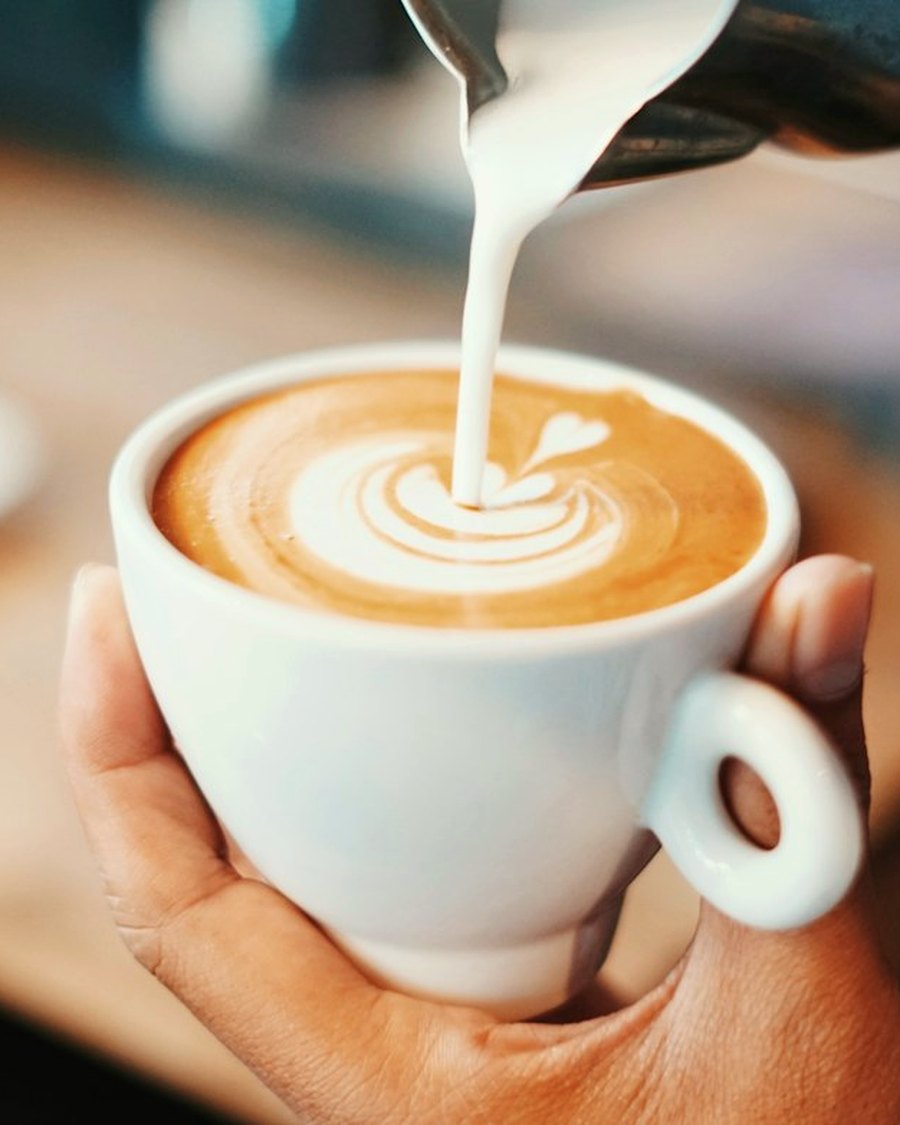Barista sirviendo leche en una taza de café de especialidad